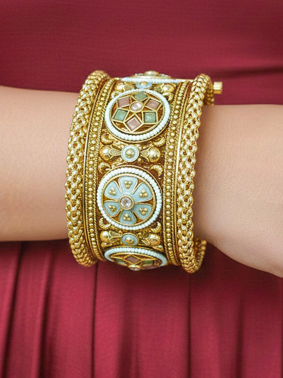 Close-up of a woman wearing an ornate traditional Rajwadi gold Bangle with Mint Pink & Mint Green Colored Stone, Meenakari, Bandhai Work and Pearls. Woman wearing bridal artificial Rajwadi bangles for a grand celebration. Luxury artificial Rajwadi bangles styled for a wedding function. Close-up of high-quality imitation Meenakari bangles for bridal wear.
