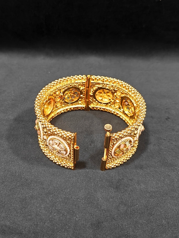 Close-up of an ornate traditional Rajwadi gold Bangle with Mint Pink & Mint Green Colored Stone, Meenakari, Bandhai Work and Pearls. Traditional Indian bridal jewelry look with artificial bangles.
Luxury artificial Rajwadi bangles styled for a wedding function. Close-up of high-quality imitation Meenakari bangles for bridal wear.