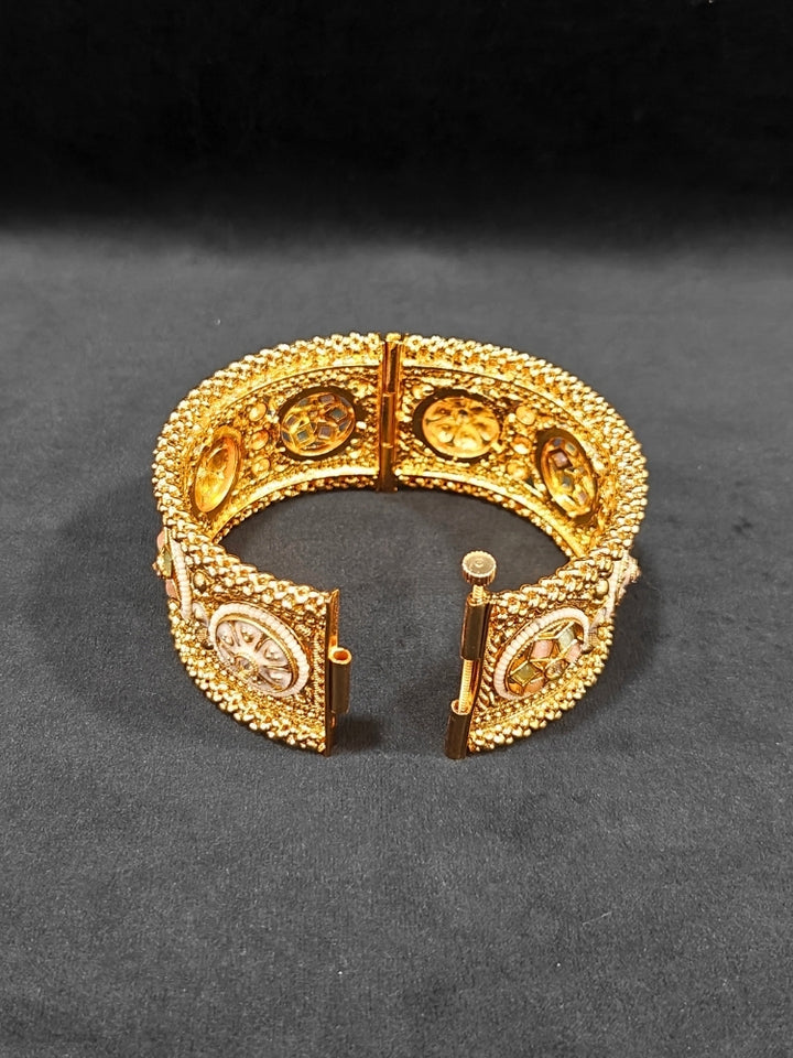 Close-up of an ornate traditional Rajwadi gold Bangle with Mint Pink & Mint Green Colored Stone, Meenakari, Bandhai Work and Pearls. Traditional Indian bridal jewelry look with artificial bangles.
Luxury artificial Rajwadi bangles styled for a wedding function. Close-up of high-quality imitation Meenakari bangles for bridal wear.