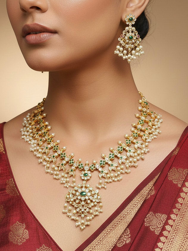 Close-up of a woman wearing an ornate traditional collar jadau gold jewellery set and jadau earrings with pearls , Kundan, Green Color Stone. Saree look enhanced with a traditional Jadau artificial necklace. Bridal styling inspiration with a premium Jadau imitation necklace.