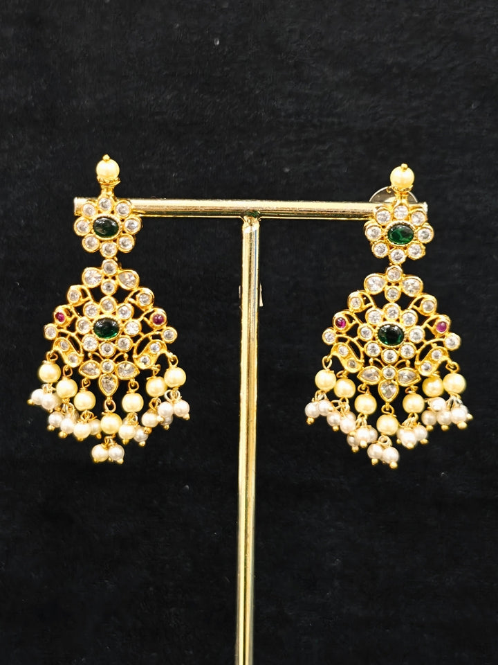 Close-up of an ornate traditional collar jadau gold jewellery set and jadau earrings with pearls , Kundan, Green Color Stone. Mehendi function outfit styled with a Jadau necklace. Close-up of a luxury Jadau imitation necklace styled with a lehenga.