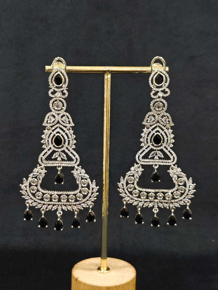 Close-up of an ornate Western Black (Silver Polish) Long Diamond Earrings with American Diamond and Colored Stones. Close-up of American diamond earrings styled for a reception party. Elegant party wear styled with high-quality imitation American Diamond earrings.