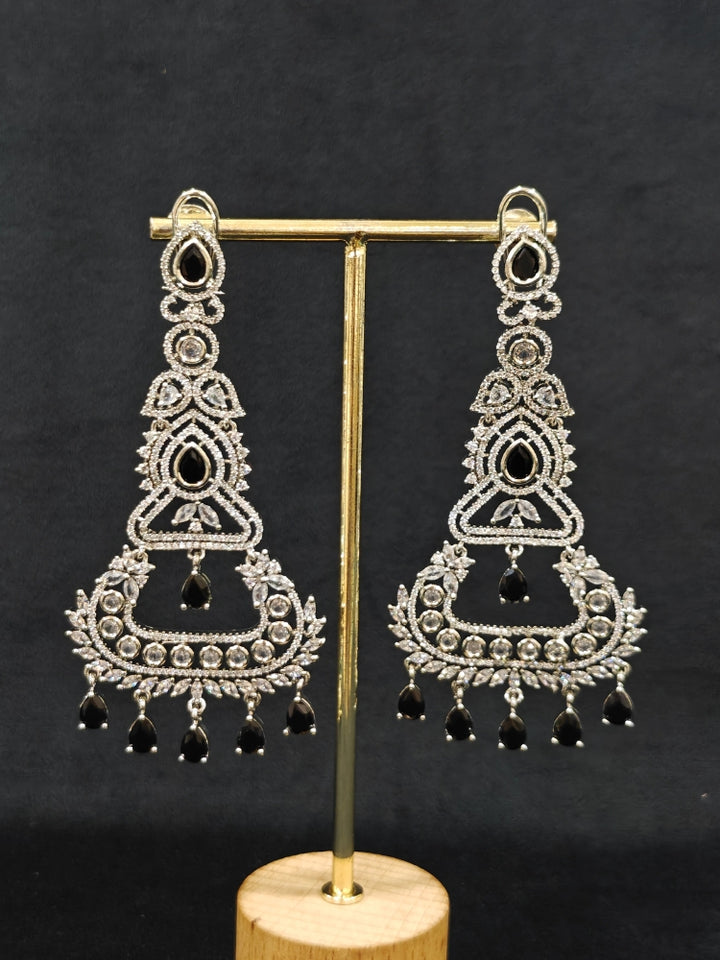 Close-up of an ornate Western Black (Silver Polish) Long Diamond Earrings with American Diamond and Colored Stones. Close-up of American diamond earrings styled for a reception party. Elegant party wear styled with high-quality imitation American Diamond earrings.