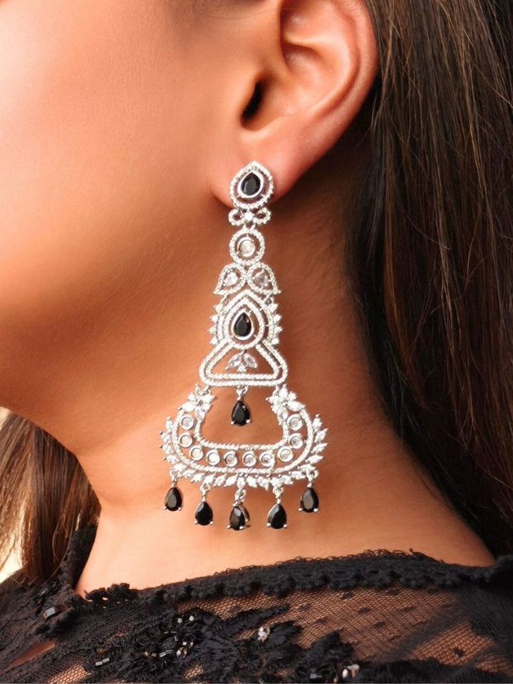 Close-up of a woman’s ear adorned with Black Kimaya Earrings—ornate chandelier style with intricate detailing, black stone accents, and multiple dangling teardrop black stones. She wears a black lace-detailed outfit.