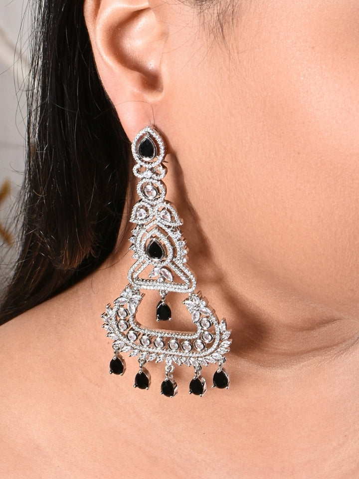Close-up of a woman wearing an ornate Western Black (Silver Polish) Long Diamond Earrings with American Diamond and Colored Stones. Close-up of American diamond earrings styled for a reception party. Elegant party wear styled with high-quality imitation American Diamond earrings.