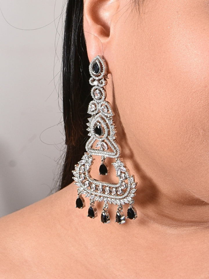 Close-up of a woman wearing an ornate Western Black (Silver Polish) Long Diamond Earrings with American Diamond and Colored Stones. Close-up of American diamond earrings styled for a reception party. Elegant party wear styled with high-quality imitation American Diamond earrings.
