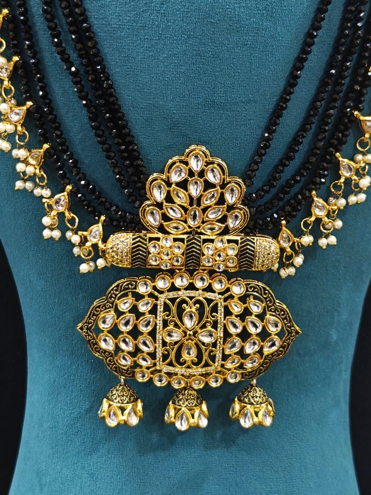 Close-up of an ornate traditional Black Meenakari gold Long jewellery set and earrings with Kundan, Meenakari work, crystal beads, pearls and American Diamonds. Wedding function styling with a premium Meenakari imitation necklace. Close-up of enamel work in Meenakari artificial wedding jewelry.