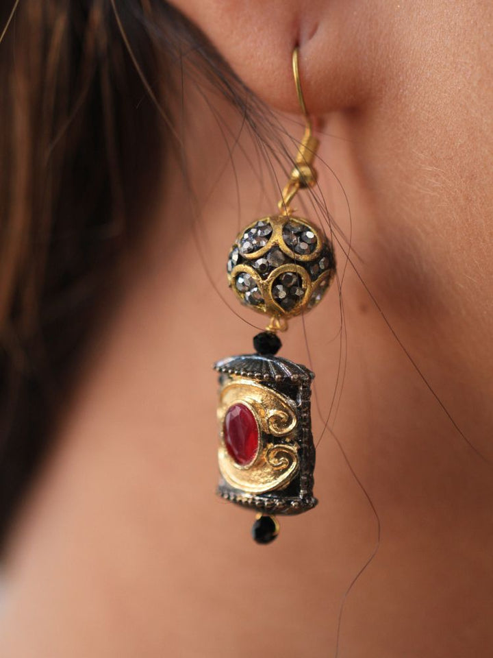 The Black Trisha Necklace Set is a decorative statement accessory with gold and black beads, square accents, and ruby and gold foil work, beautifully displayed on a girl in black attire with gold design on it. 