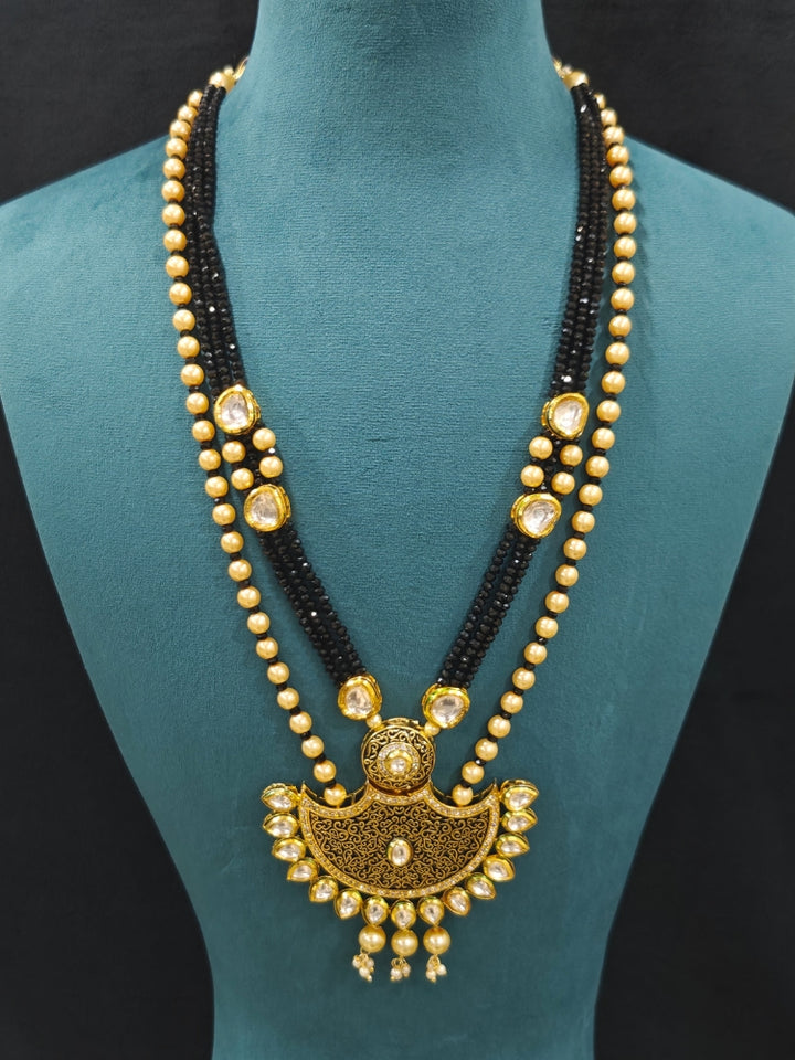 Close-up of an ornate traditional Black Meenakari Long  jewellery set and earrings with Kundan, Meenakari work, crystal beads, pearls and American Diamond. Mehendi ceremony look completed with a Meenakari jewelry set. A vibrant Meenakari artificial jewelry set for celebrations.