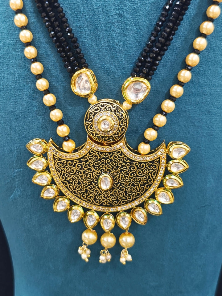 Close-up of an ornate traditional Black Meenakari Long  jewellery set and earrings with Kundan, Meenakari work, crystal beads, pearls and American Diamond. Mehendi ceremony look completed with a Meenakari jewelry set. A vibrant Meenakari artificial jewelry set for celebrations.