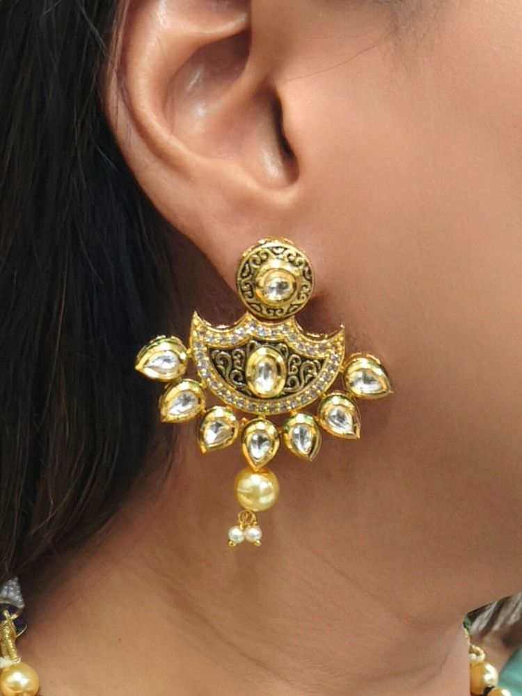 A girl in a deep sea gree  sari showcases the Black Zareen Necklace Set, featuring gold and black tones with pearl accents, matching earrings, intricate designs, american diamonds, and elegant Kundan detailing.