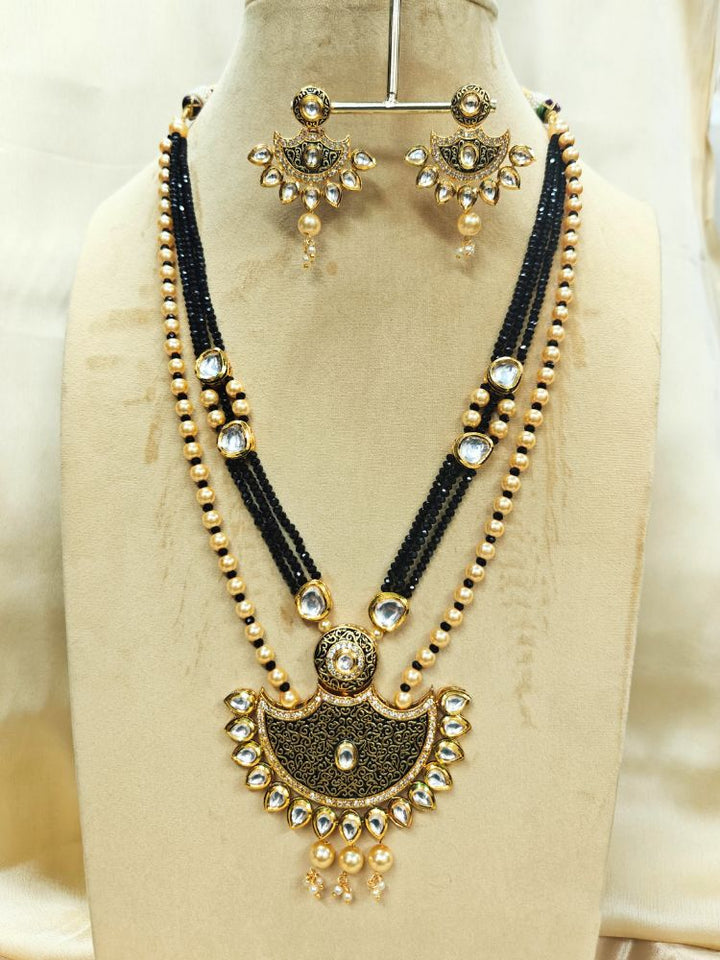 A cream mannequin showcases the Black Zareen Necklace Set, featuring gold and black tones with pearl accents, matching earrings, intricate designs, american diamonds, and elegant Kundan detailing.