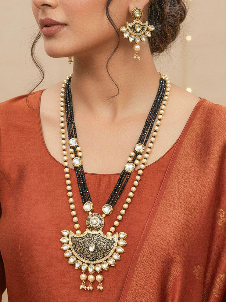 Close-up of a woman wearing an ornate traditional Black Meenakari Long  jewellery set and earrings with Kundan, Meenakari work, crystal beads, pearls and American Diamond. Mehendi ceremony look completed with a Meenakari jewelry set. Woman wearing a vibrant Meenakari artificial jewelry set for celebrations.