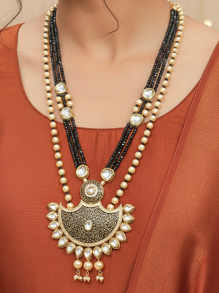 Close-up of a woman wearing an ornate traditional Black Meenakari Long  jewellery set and earrings with Kundan, Meenakari work, crystal beads, pearls and American Diamond. Mehendi ceremony look completed with a Meenakari jewelry set. Woman wearing a vibrant Meenakari artificial jewelry set for celebrations.