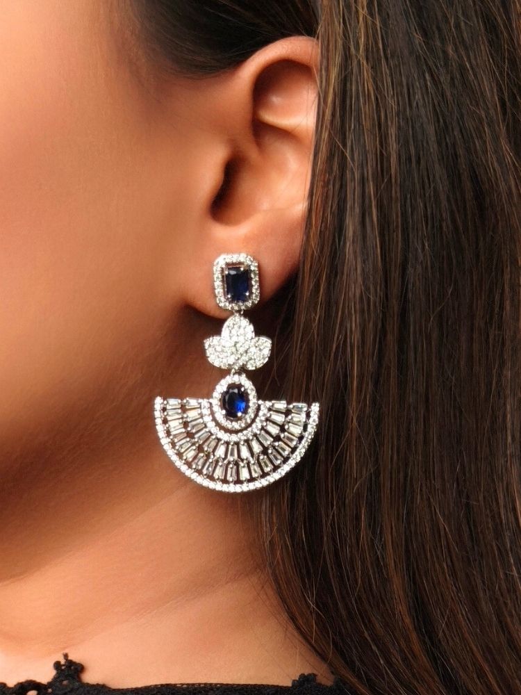 Close-up of a woman wearing an ornate Western (Silver Polish) Blue Diamond Earrings with American Diamond and Colored Stones. Reception-ready look featuring a statement American diamond Earrings set. Elegant wedding jewelry look featuring a premium artificial American diamond Earrings.