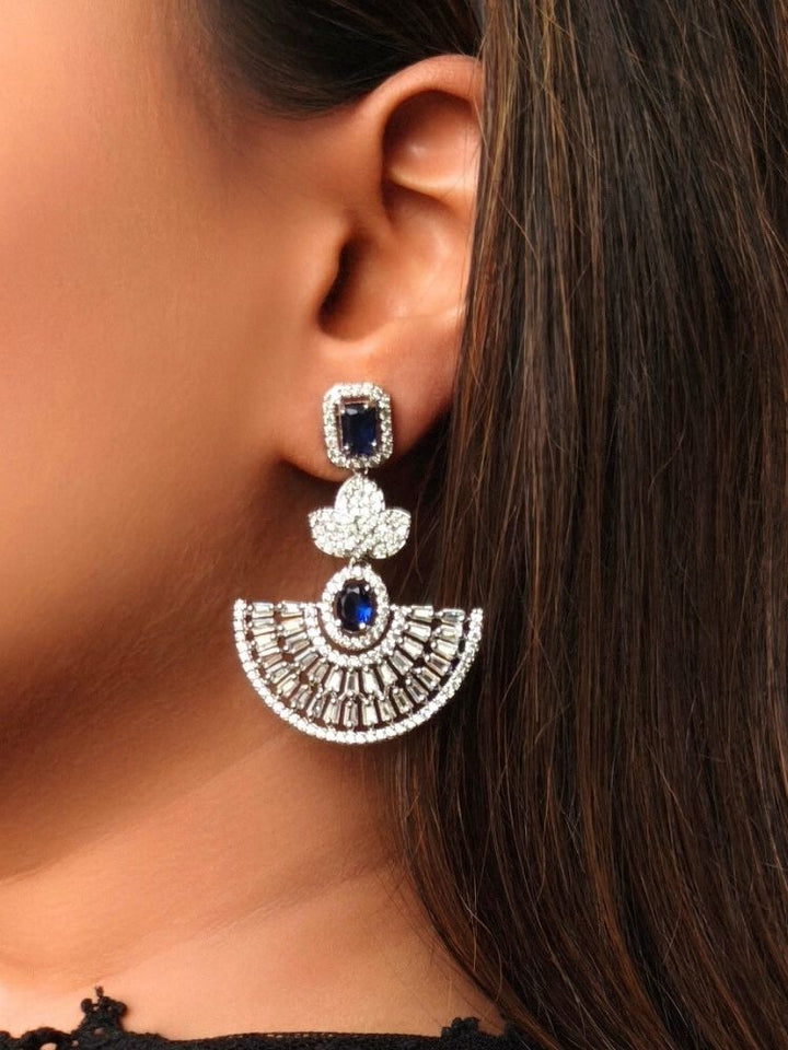 Close-up of a woman wearing an ornate Western (Silver Polish) Blue Diamond Earrings with American Diamond and Colored Stones. Reception-ready look featuring a statement American diamond Earrings set. Elegant wedding jewelry look featuring a premium artificial American diamond Earrings.