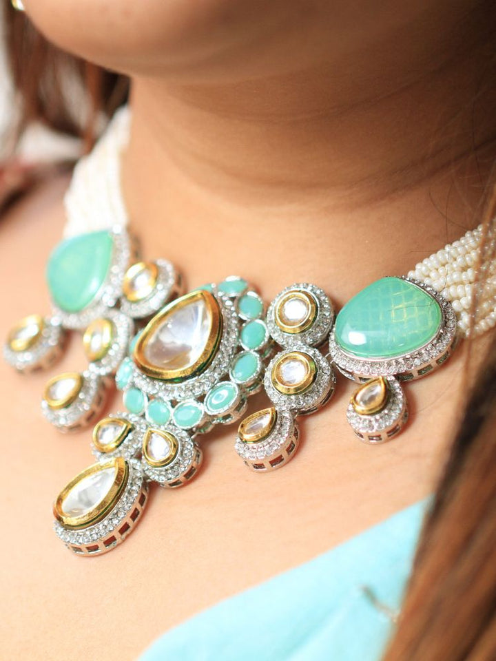 A woman in a  Red outfit smiles, showcasing the Peacoski Blue Tamanna Necklace Set and matching earrings. Her soft makeup highlights the elegance of this statement jewelry ensemble.