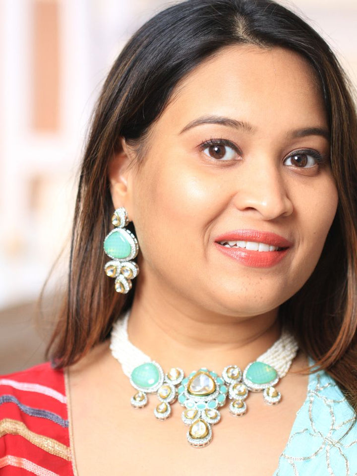 A woman in a  Red outfit smiles, showcasing the Peacoski Blue Tamanna Necklace Set and matching earrings. Her soft makeup highlights the elegance of this statement jewelry ensemble.