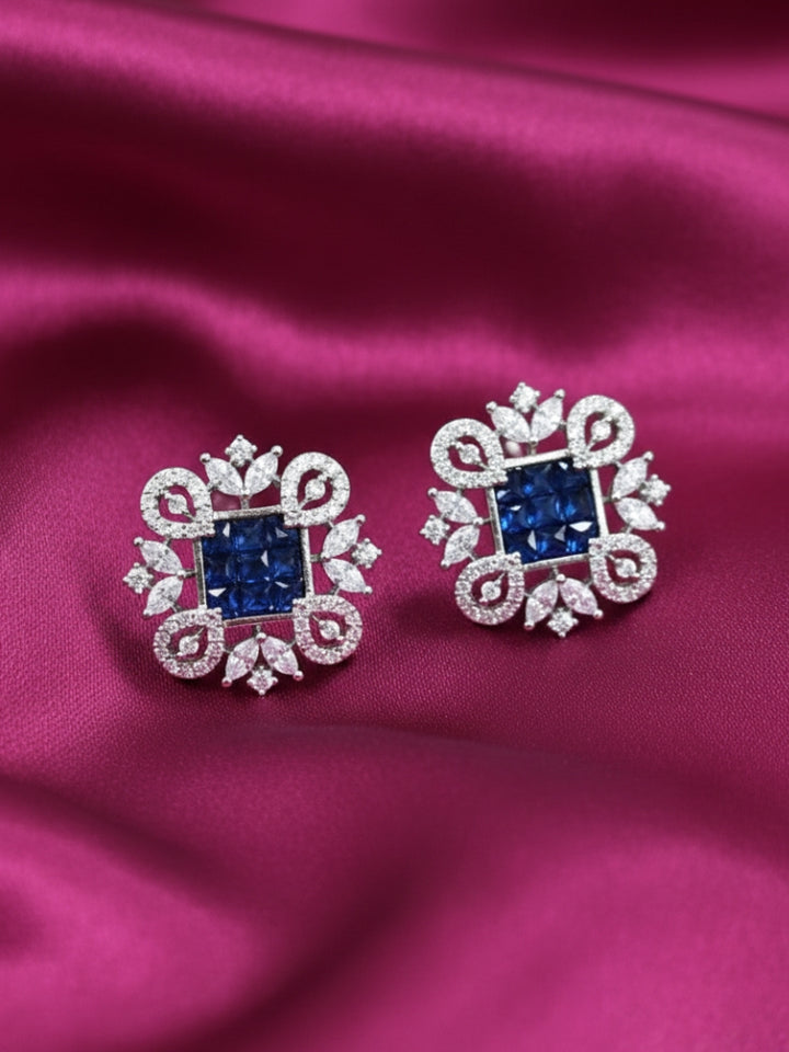 Close-up of an ornate Western (Silver Polish) Blue Diamond Studs Earrings with American Diamond. western dress styled with lightweight artificial American Diamond studs earrings. Wear in office and everyday.