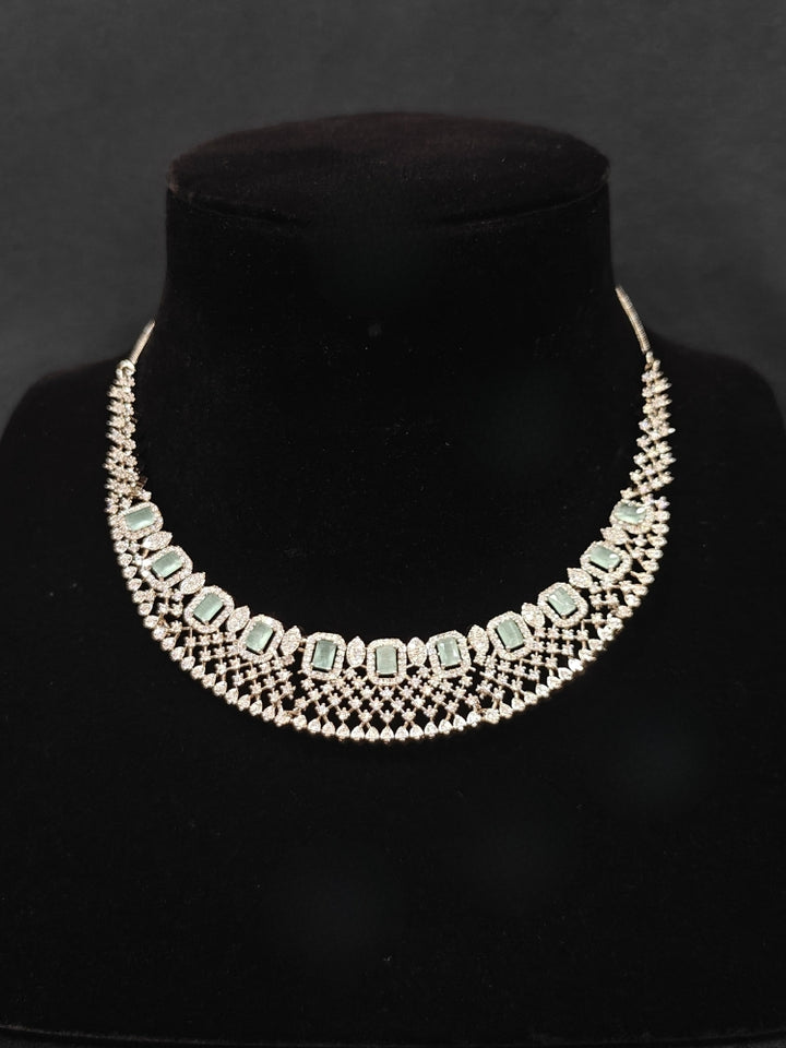 Close-up of an ornate Western Mint Green (Silver Polish) Collar Diamond jewellery set and earrings with American Diamond and Mint Green Colored Stones. A lightweight American diamond necklace perfect for long wedding functions. 