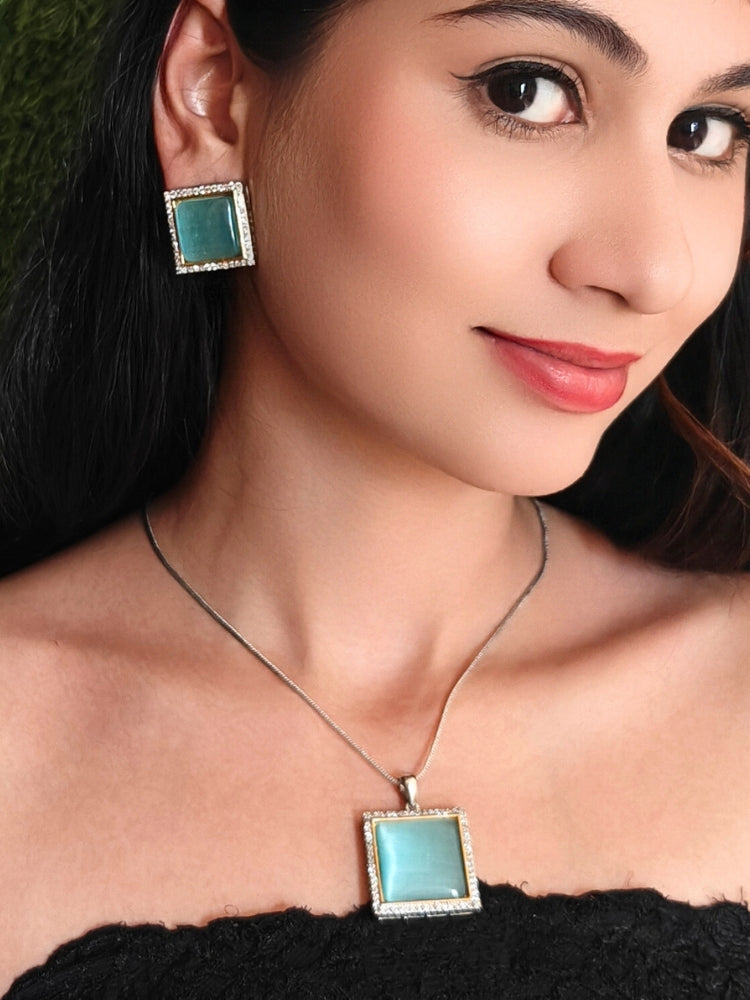 Close-up of a woman wearing an ornate traditional (Silver Polish) Blue Pendant set and earrings with American Diamond and Blue Colored Stone. Close-up of a cocktail party look featuring a premium Colored Stone Pendant Set. Party wear outfit completed with a lightweight Colored Stone Pendant Set.