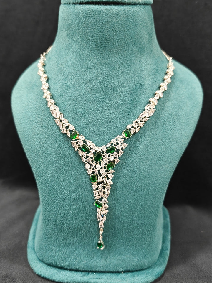Close-up of a diamond and emerald necklace with green colored stone and  matching earrings. This premium artificial diamond jewelry set is perfect for special occasions, from Indian weddings to engagement parties, offering sophisticated glamour without the high price tag.