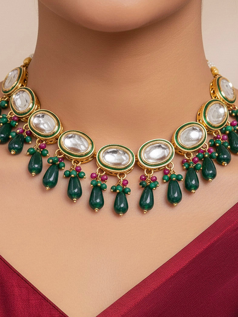 Close-up of a woman wearing an ornate traditional (Gold Polish) Dark Green Collar jewellery set and earrings with Kundan, Red and Green small beads and Tumble Stone. Mehendi ceremony look completed with a handcrafted Kundan jewelry set. Festive saree styling with a premium artificial Kundan necklace. Perfect Necklace for Wedding Function and Festive.