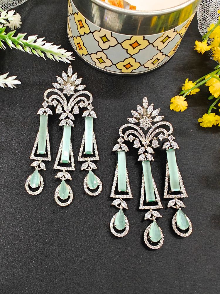 Chandelier Mint Green Earrings featuring ornate designs with mint Green stones and clear crystals, ideal for cocktail parties, displayed on a black surface next to yellow flowers and a decorative container.