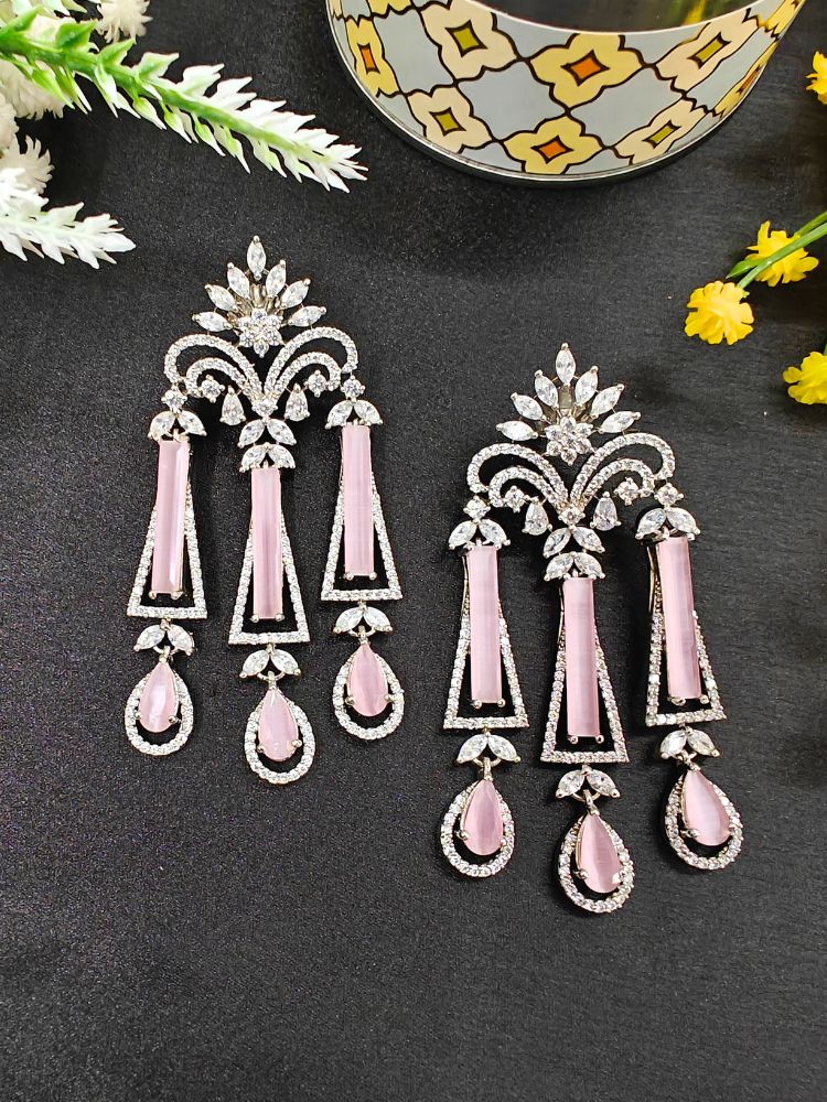 Chandelier Mint Pink Earrings featuring ornate designs with mint pink stones and clear crystals, ideal for cocktail parties, displayed on a black surface next to yellow flowers and a decorative container.