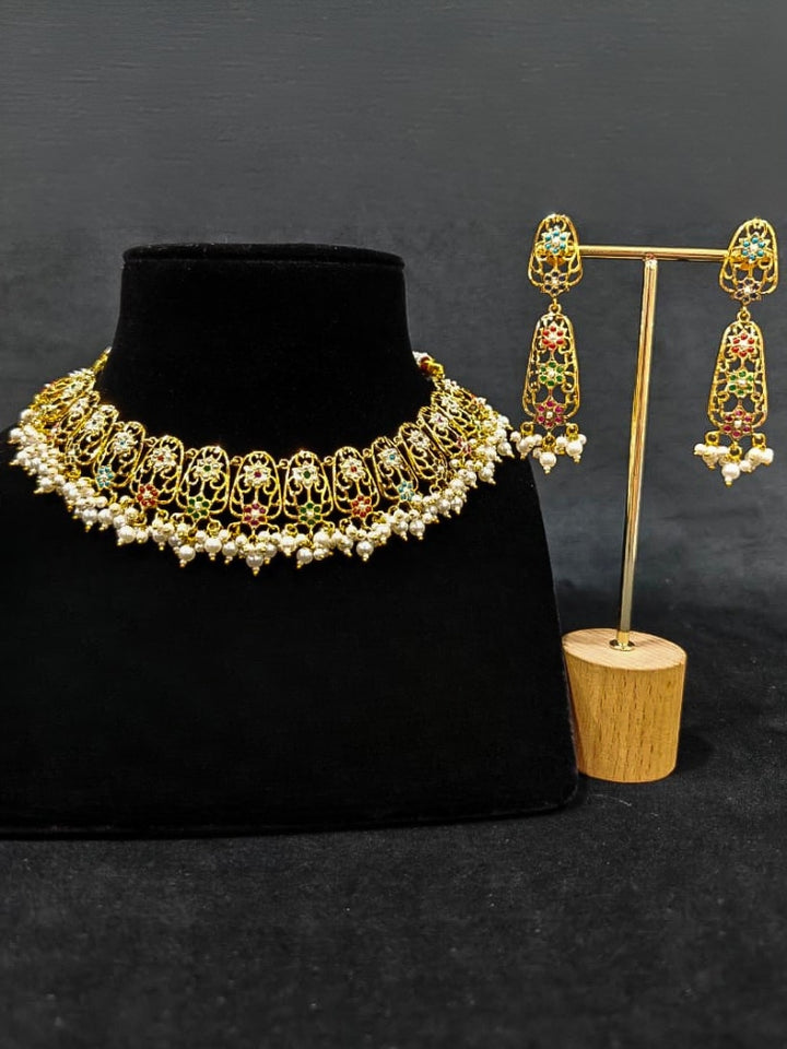 Close-up of an ornate traditional Navratan jadau gold jewellery set and jadau earrings with navratan color stone and Pearls. Close-up of intricate Jadau detailing in artificial jewelry. A royal Jadau necklace for festive events in India.