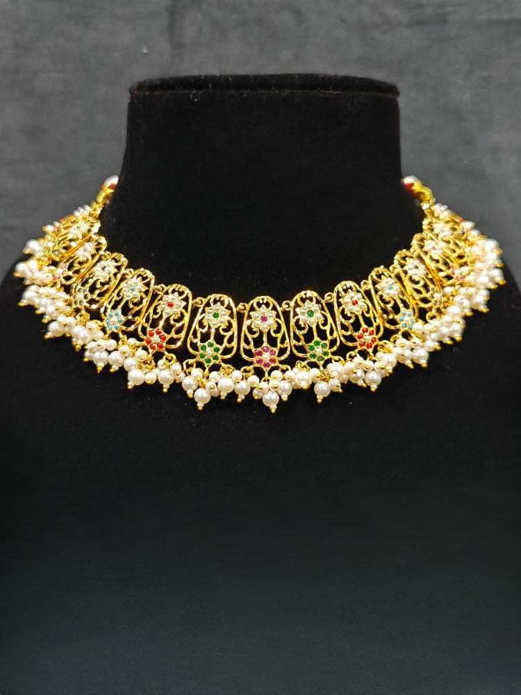 Close-up of an ornate traditional Navratan jadau gold jewellery set and jadau earrings with navratan color stone and Pearls. Close-up of intricate Jadau detailing in artificial jewelry. A royal Jadau necklace for festive events in India.