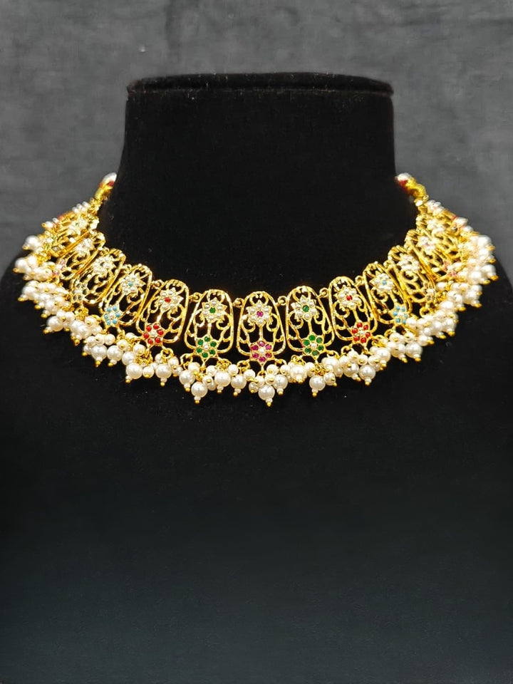 Close-up of an ornate traditional Navratan jadau gold jewellery set and jadau earrings with navratan color stone and Pearls. Close-up of intricate Jadau detailing in artificial jewelry. A royal Jadau necklace for festive events in India.
