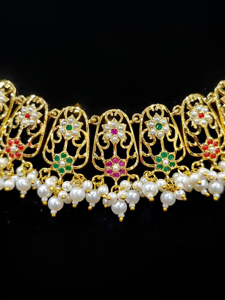 Close-up of an ornate traditional Navratan jadau gold jewellery set and jadau earrings with navratan color stone and Pearls. Close-up of intricate Jadau detailing in artificial jewelry. A royal Jadau necklace for festive events in India.