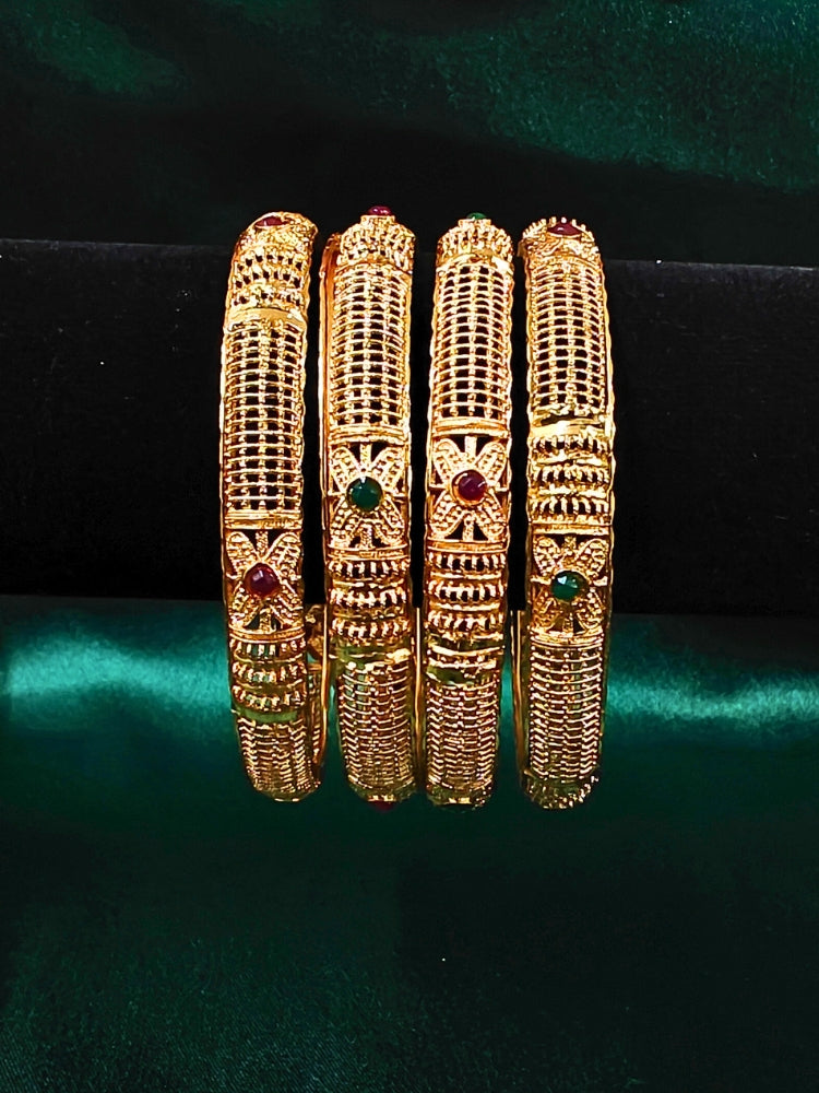Set of gold bangles with gemstones on a dark background