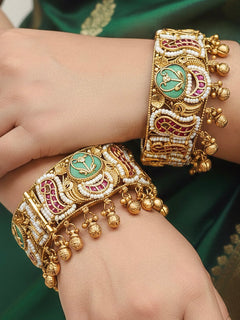 Close-up of a woman wearing an ornate traditional Heritage (Gold Polish) Mint Green Bangles Set with Kundan, Pearl and Colored Stones. Bride wearing traditional artificial Heritage bangles for her wedding ceremony in India. Close-up of premium imitation Heritage bangles styled with a silk saree.