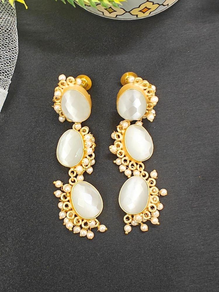 The Chloe long Earrings feature three oval milky stones on each piece, accented by  pearls and set against a golden fabric background—an elegant choice to complement your wedding ceremony dress.