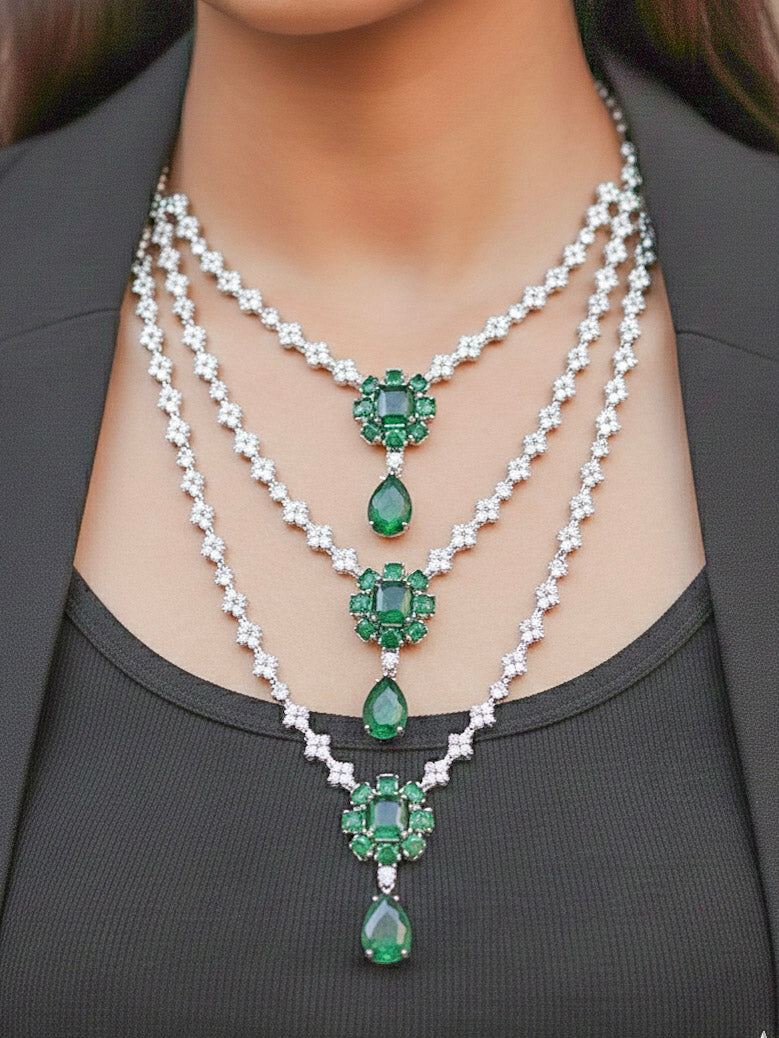 Close-up of a woman wearing an ornate Western American Diamond layered Silver jewellery set, Earrings and Ring with American Diamond and Green Colored Stones. Party wear outfit completed with a lightweight American diamond necklace. Close-up of a cocktail party look featuring a premium American diamond necklace.