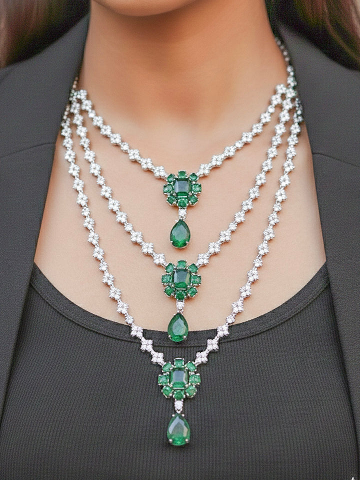 Close-up of a woman wearing an ornate Western American Diamond layered Silver jewellery set, Earrings and Ring with American Diamond and Green Colored Stones. Party wear outfit completed with a lightweight American diamond necklace. Close-up of a cocktail party look featuring a premium American diamond necklace.