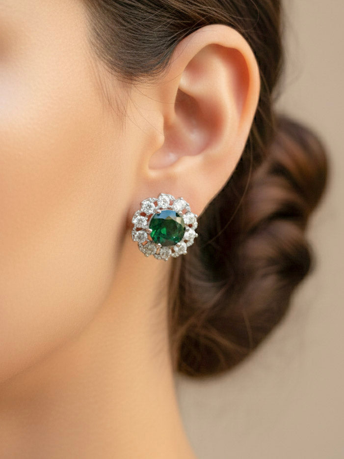 Close-up of a woman wearing an ornate Western American Diamond layered Silver jewellery set, Earrings and Ring with American Diamond and Green Colored Stones. Party wear outfit completed with a lightweight American diamond necklace. Close-up of a cocktail party look featuring a premium American diamond necklace.