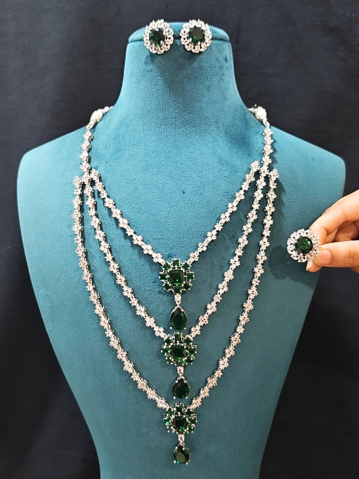 Close-up of an ornate Western American Diamond layered Silver jewellery set, Earrings and Ring with American Diamond and Green Colored Stones. Party wear outfit completed with a lightweight American diamond necklace. Close-up of a cocktail party look featuring a premium American diamond necklace.