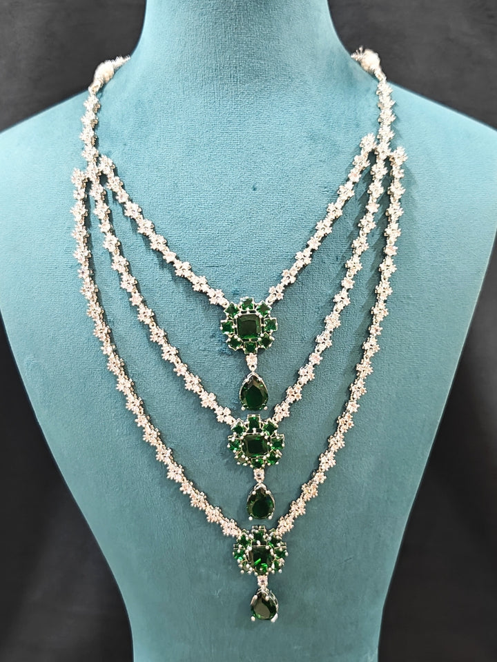 Close-up of an ornate Western American Diamond layered Silver jewellery set, Earrings and Ring with American Diamond and Green Colored Stones. Party wear outfit completed with a lightweight American diamond necklace. Close-up of a cocktail party look featuring a premium American diamond necklace.