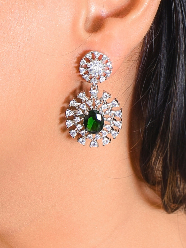 A woman adorns herself with the Cressida Green Necklace Set, featuring sparkling American Diamond necklace,  highlighted by a striking green gemstone in the center. This necklace set comes along with matching earrings. The jewelry intricate design elegantly enhances her look.