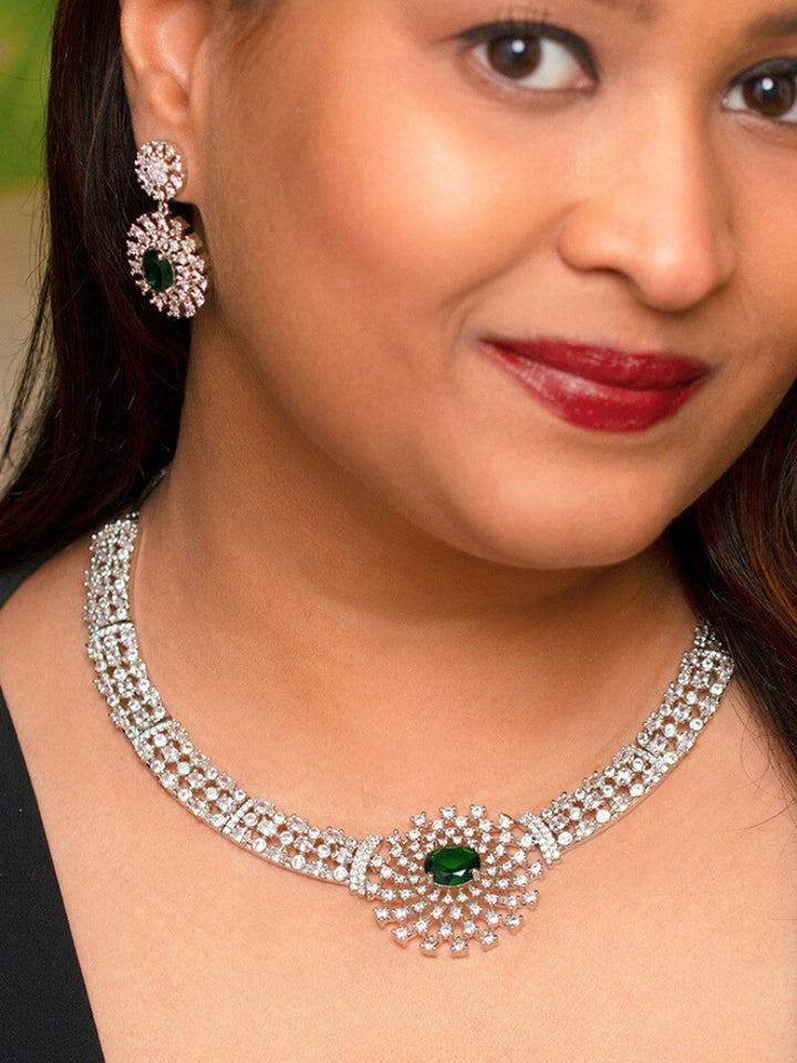 A close-up shot of a bride wearing a stunning artificial diamond necklace with emerald green colored stone and matching earrings, designed to complement bridal attire. This affordable diamond necklace set is perfect for brides seeking luxurious but cost-effective wedding jewelry in India.