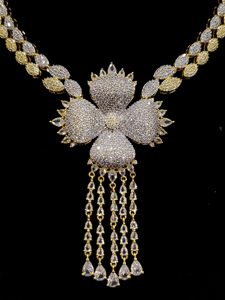 A glamorous artificial diamond necklace paired with chic earrings and maangtikka, perfect for bridal wear. This high-quality artificial diamond jewelry set. Close-up of a cocktail party look featuring a premium American diamond necklace.