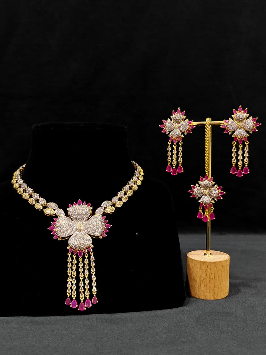 An exquisite artificial diamond necklace with pink colored stone and matching earrings and maangtikka, designed for the perfect engagement look. This stunning artificial diamond jewelry set offers luxury and sophistication while being an affordable alternative to natural diamonds.