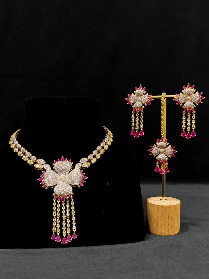 An exquisite artificial diamond necklace with pink colored stone and matching earrings and maangtikka, designed for the perfect engagement look. This stunning artificial diamond jewelry set offers luxury and sophistication while being an affordable alternative to natural diamonds.