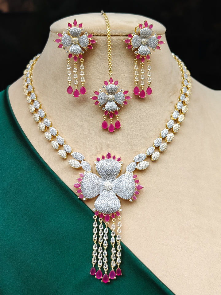 "A close-up shot of a bride wearing a stunning artificial diamond necklace with pink colored stone with matching earrings and maangtikka, designed to complement bridal attire. This affordable diamond necklace set is perfect for brides seeking luxurious but cost-effective wedding jewelry in India."
