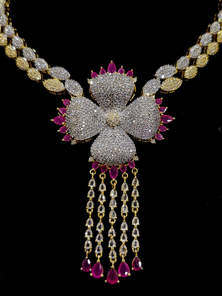 An exquisite artificial diamond necklace with pink colored stone and matching earrings and maangtikka, designed for the perfect engagement look. This stunning artificial diamond jewelry set offers luxury and sophistication while being an affordable alternative to natural diamonds.