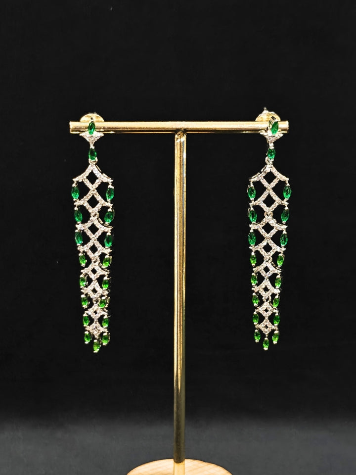 Close-up of an ornate Western (Silver Polish) Green Long Diamond Earrings with American Diamond and Colored. A lightweight American diamond Earrings perfect for long wedding functions. Close-up of a cocktail party look featuring a premium American diamond Earrings.
