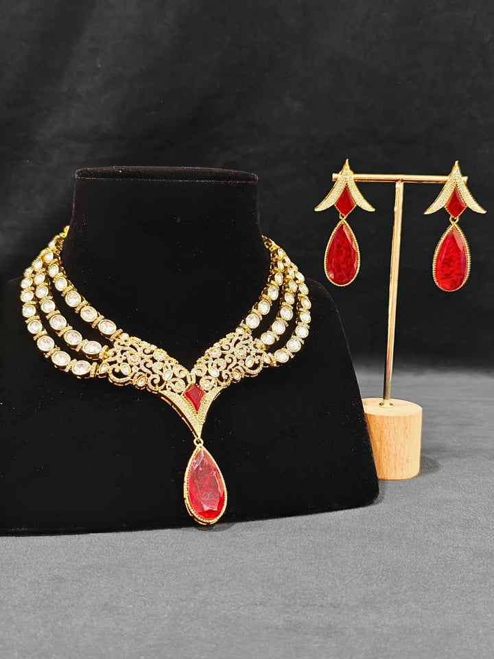 An exquisite artificial diamond and red colored stone and kundan polki necklace and matching earrings, designed for the perfect engagement look. This stunning artificial diamond jewelry set offers luxury and sophistication while being an affordable alternative to natural diamonds."